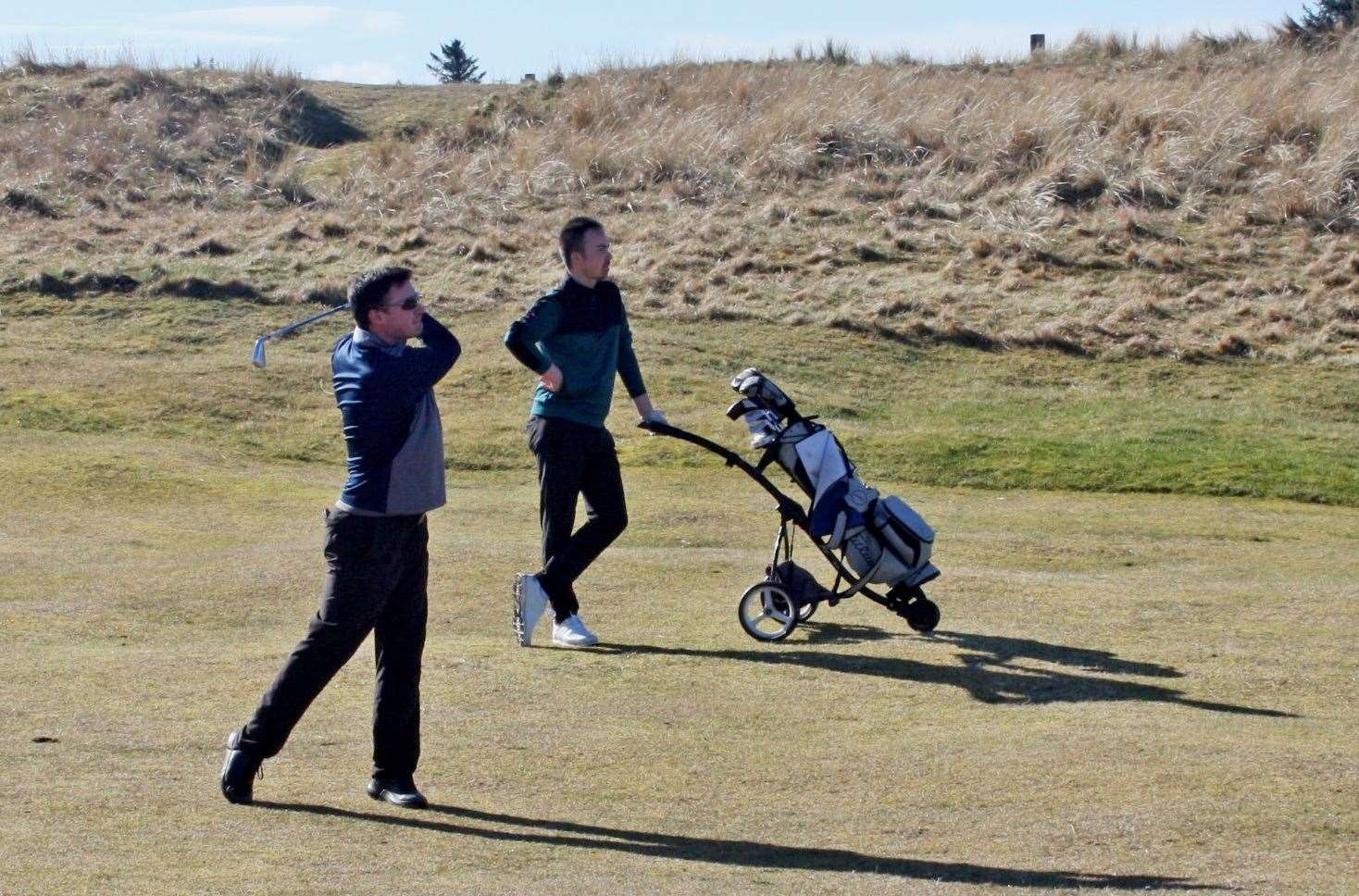 Michael Smith, runner-up in the scratch section of the Ronnie Wallace Open, plays his approach to the sixth hole as scratch winner Gregor Munro looks on.