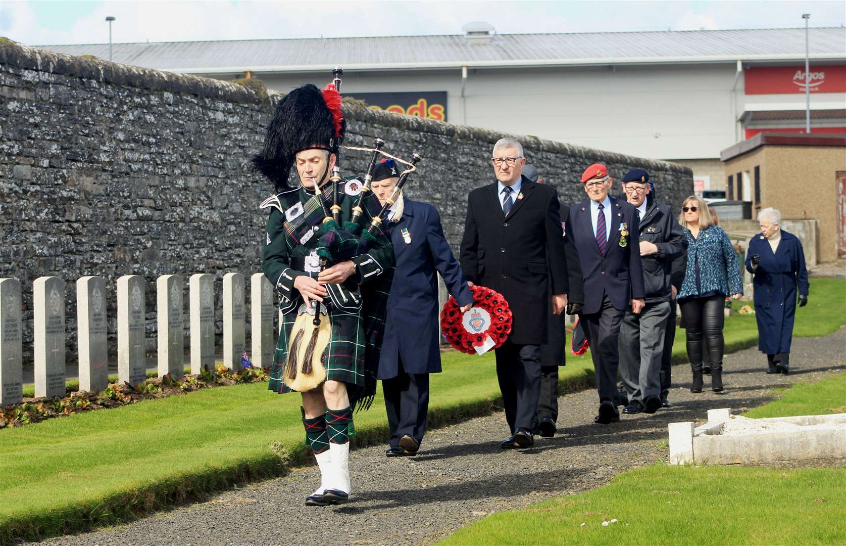Pipe Corporal Gordon Tait, of Wick RBLS Pipe Band, leads the official party towards the war graves. Picture: Alan Hendry
