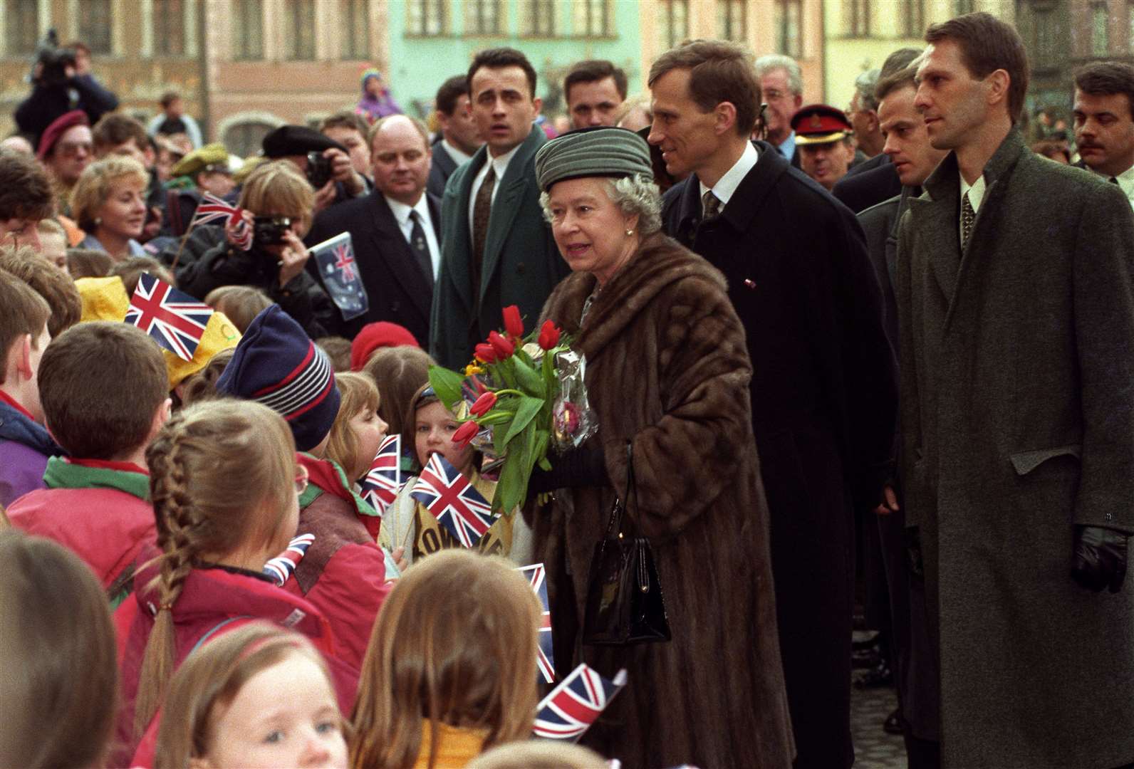 The then Queen receives a warm welcome and flowers from schoolchildren during a walkabout in the old town square, Warsaw in 1996 (John Stillwell/PA)