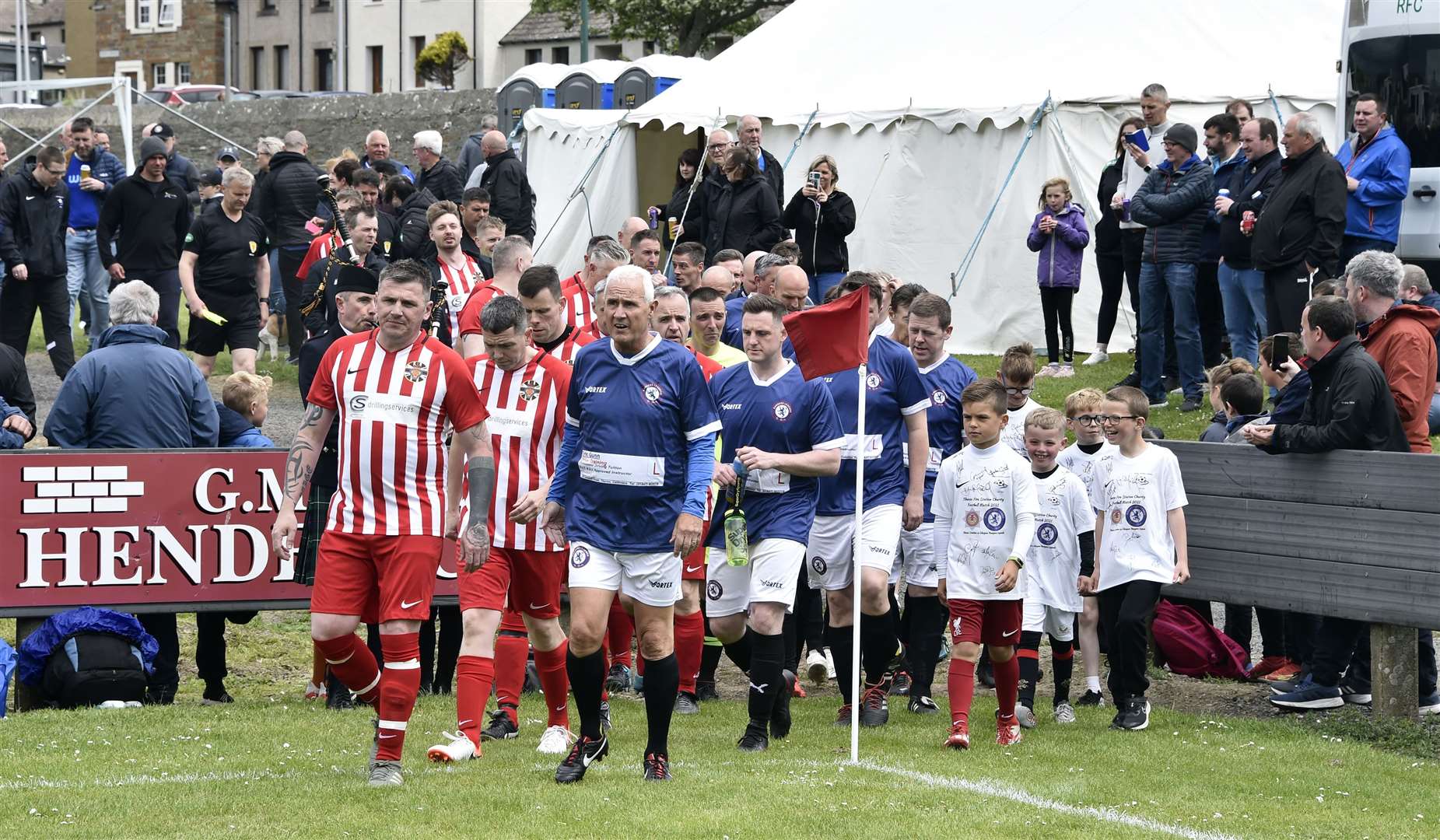 The teams heading out for the recent charity match, accompanied by mascots from Thurso Football Academy. Picture: Mel Roger