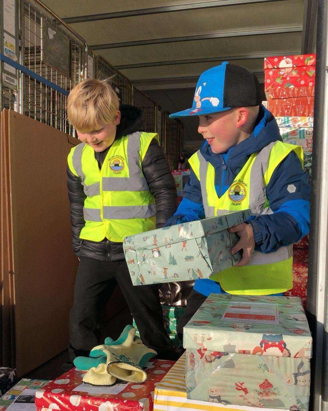 Devon Mackay (left) and Jack Gardner lend a hand with lifting boxes onto the van.