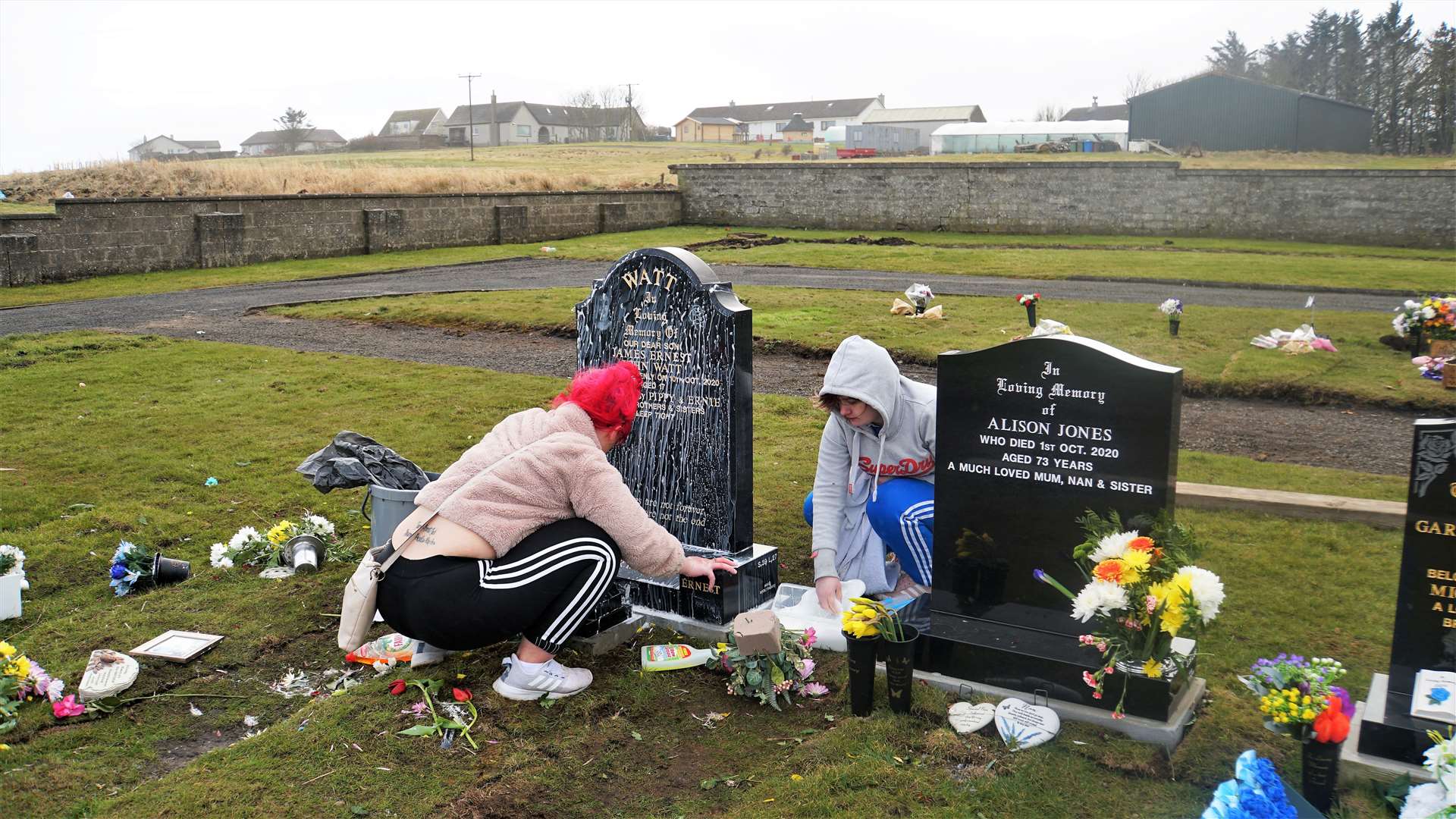 James Watt's sisters remove the white paint from his gravestone this afternoon at Wick cemetery. An empty paint can was found over the wall behind them in a neighbouring field. No other gravestones appear damaged. Pictures: DGS