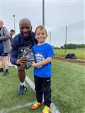 Marvin Andrews presents a pair of ArmourFlex shinguards to player of the camp (five to nine year olds) Thomas Nicholson.