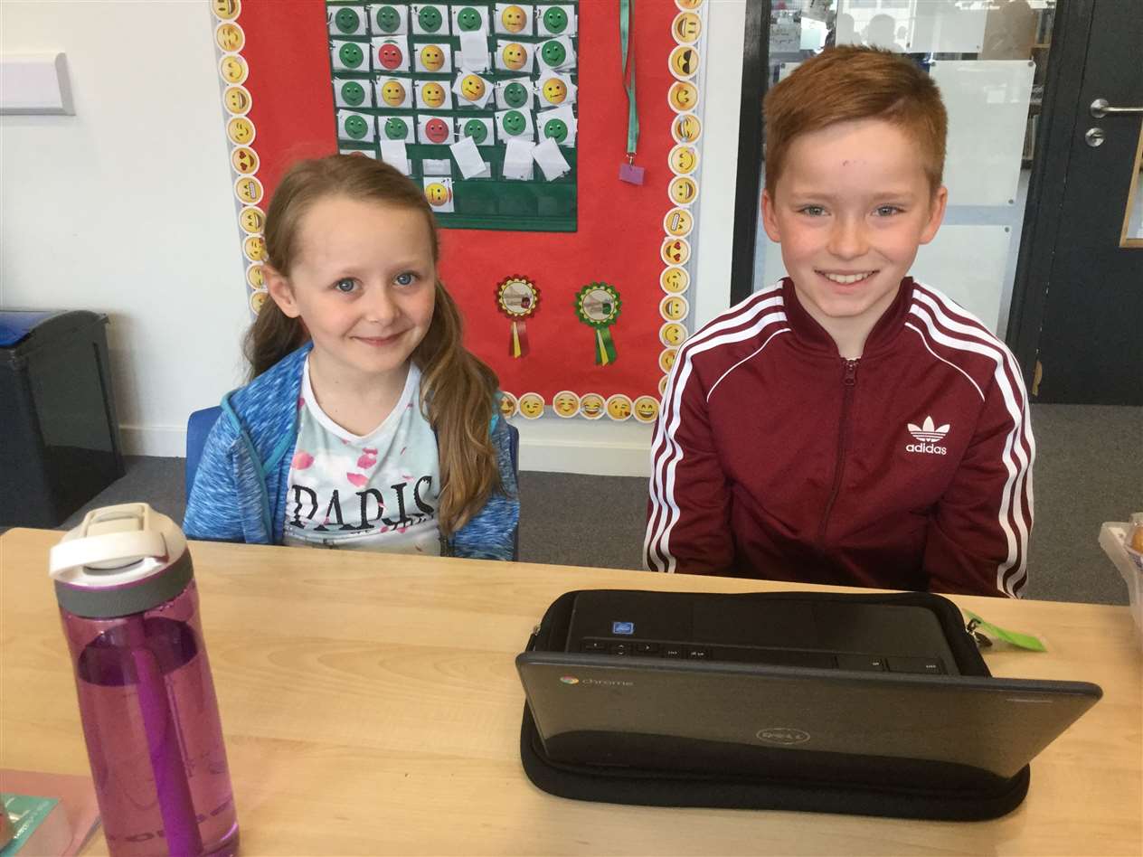 P6 pupil Joe Gill teaching P2 pupil Kara Simpson some French words using his Chromebook.