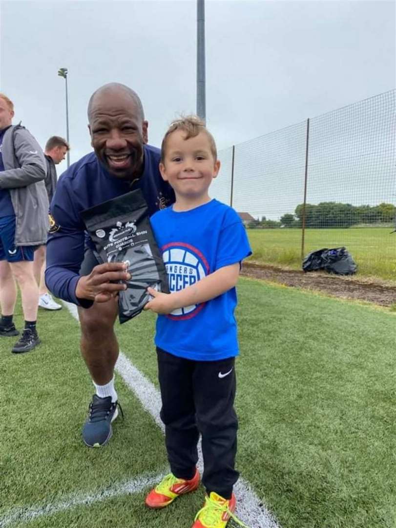 Marvin Andrews presents a pair of ArmourFlex shinguards to player of the camp (five to nine year olds) Thomas Nicholson.