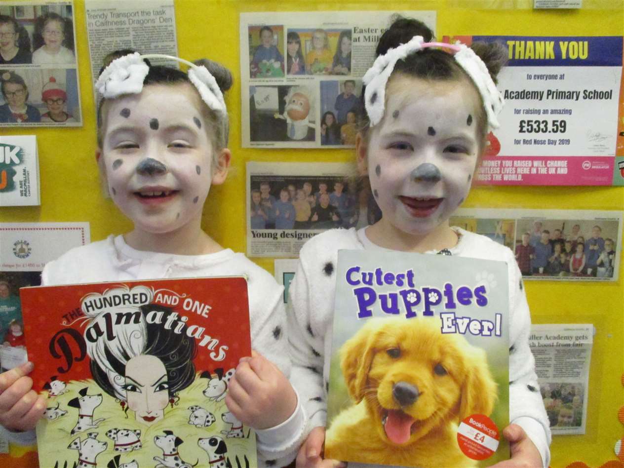 Two little primary one Dalmatians showing their books.