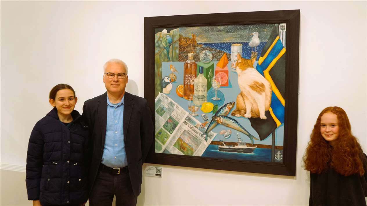 Artist Willie Wallace with his daughters and his work called Caithness Winter Warmers. The painting includes a copy of the Caithness Courier within it along with other local icons. Picture: DGS