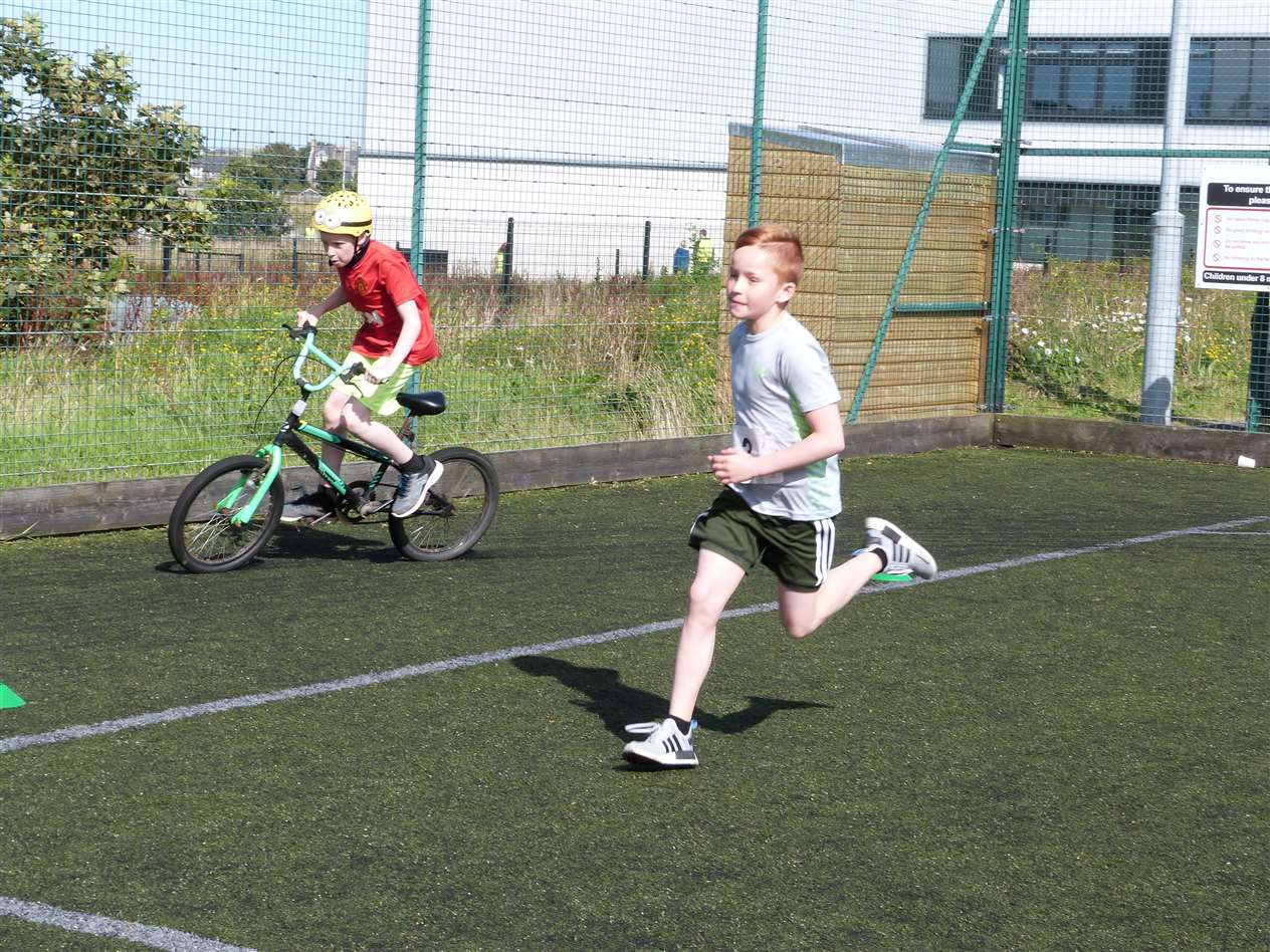 Running and cycling side by side in the junior triathlon at Wick.
