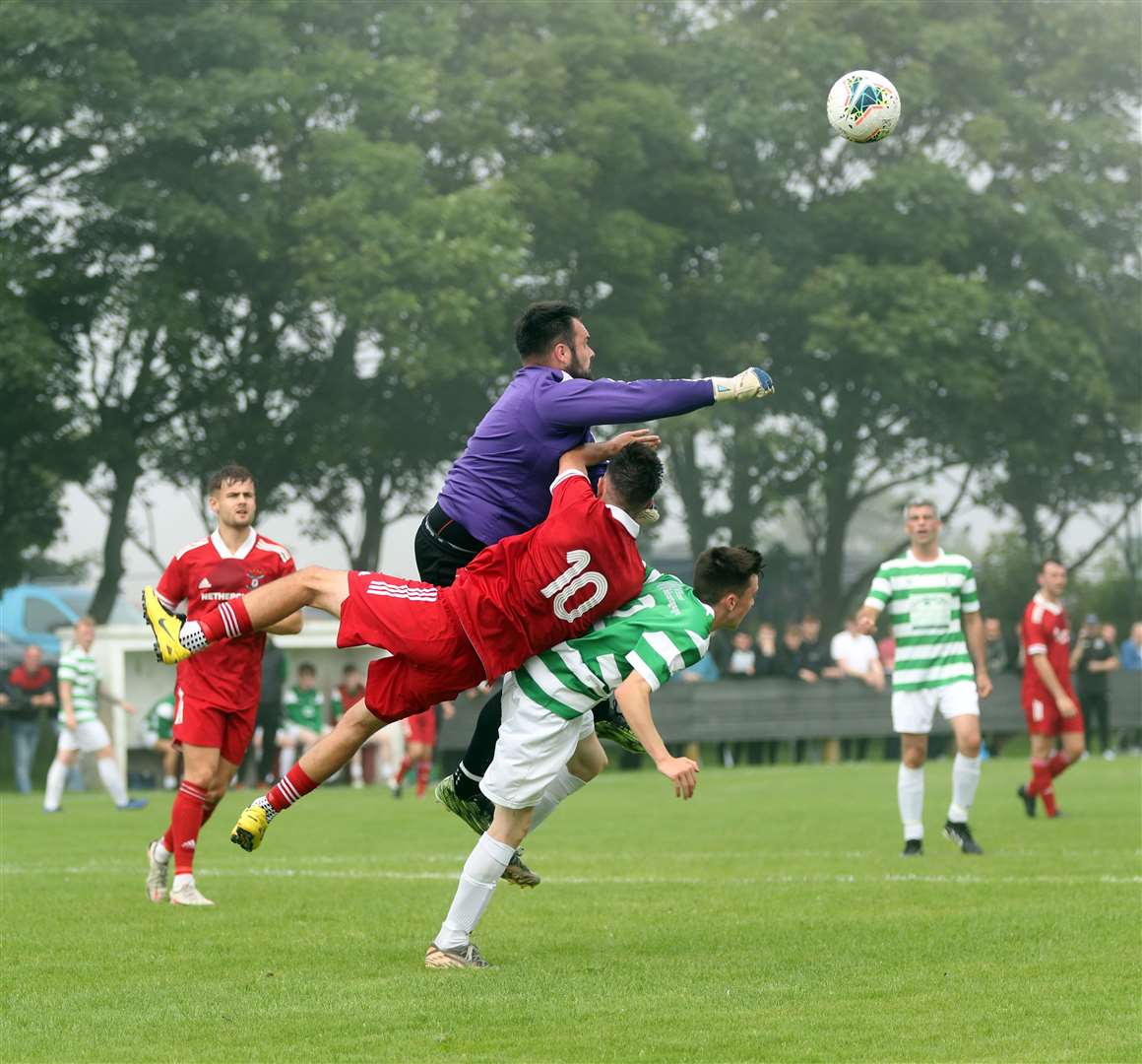 Castletown goalkeeper Gordon Clark punches clear as Graham MacNab takes a tumble. Picture: James Gunn