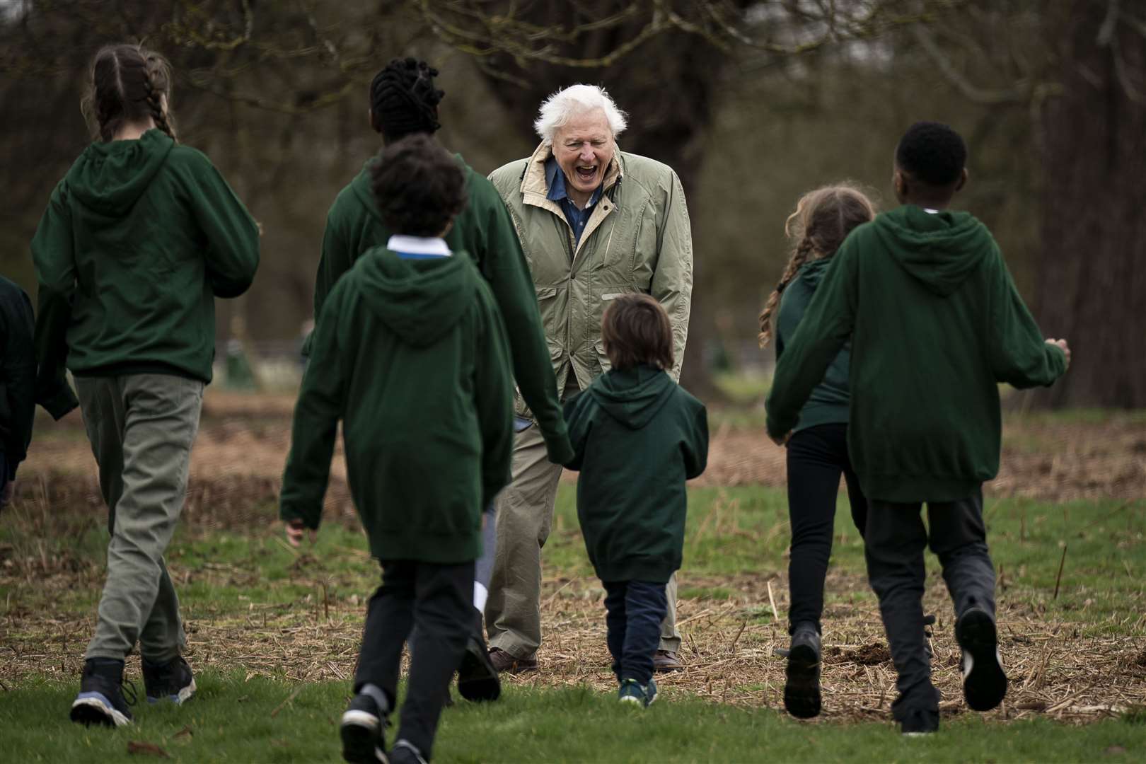 Sir David Attenborough with schoolchildren as he plants the tree in Richmond Park (Aaron Chown/PA)