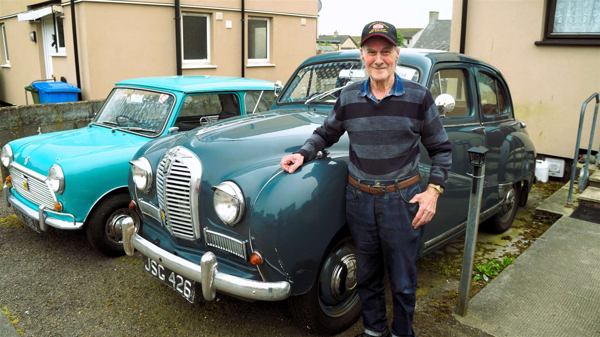 Ian with his vintage cars parked outside his home in Wick. The vehicle at far left is a Mini 1000 and the car next to him is an Austin A40 Somerset similar to the one he passed his test in. Picture: DGS
