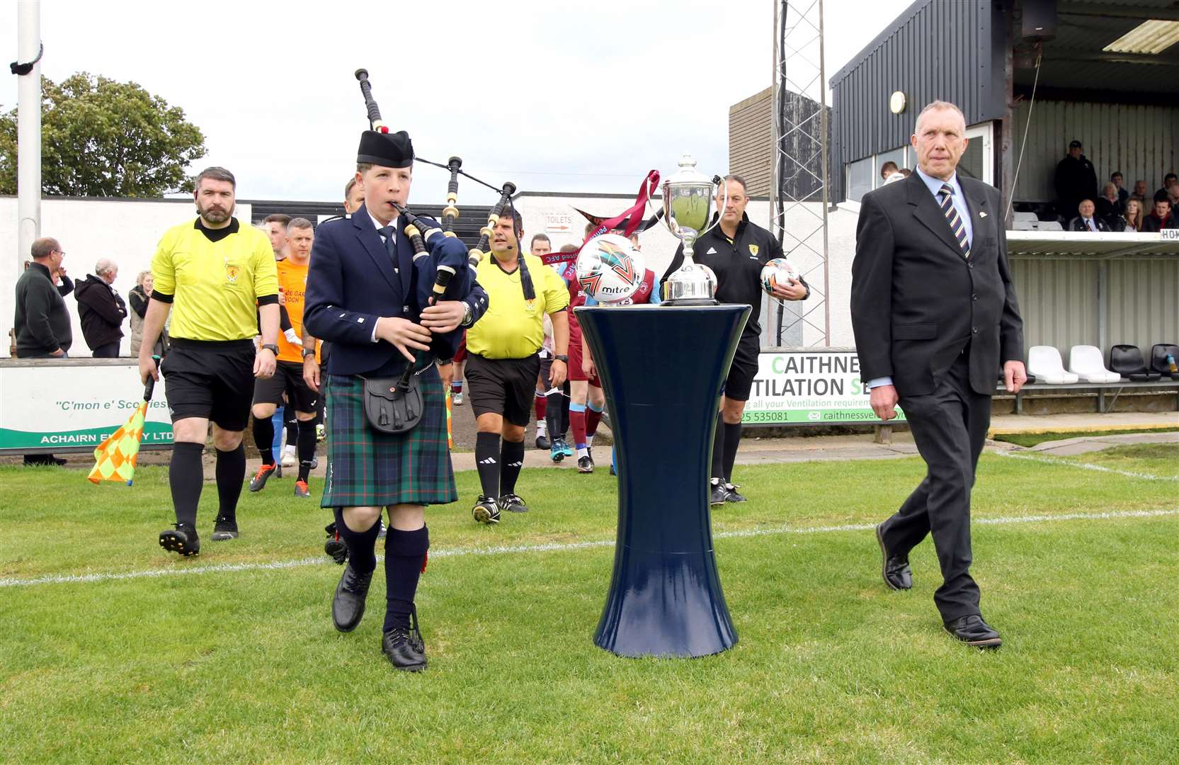 Latheron piper Andrew Sinclair leading the match officials and teams onto Harmsworth Park alongside Highland Amateur Cup secretary Bob Gunn. Picture: James Gunn