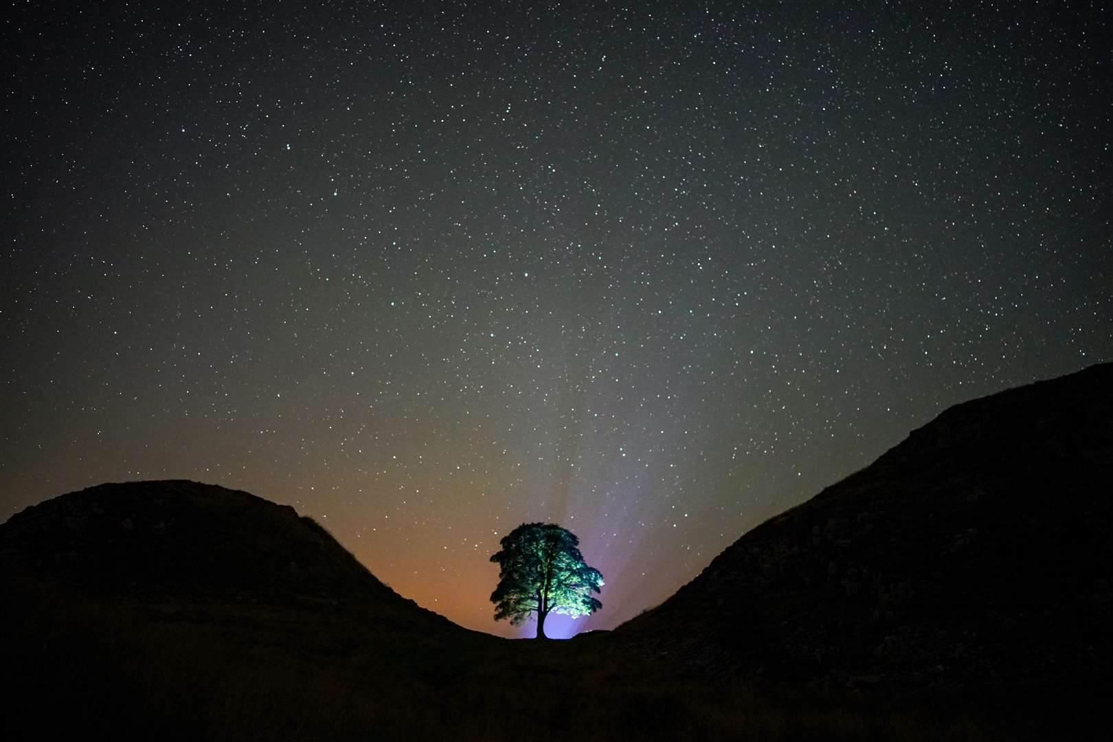 A photographer lines up a shot on a clear night under the Milky Way at Sycamore Gap (Owen Humphreys/PA)