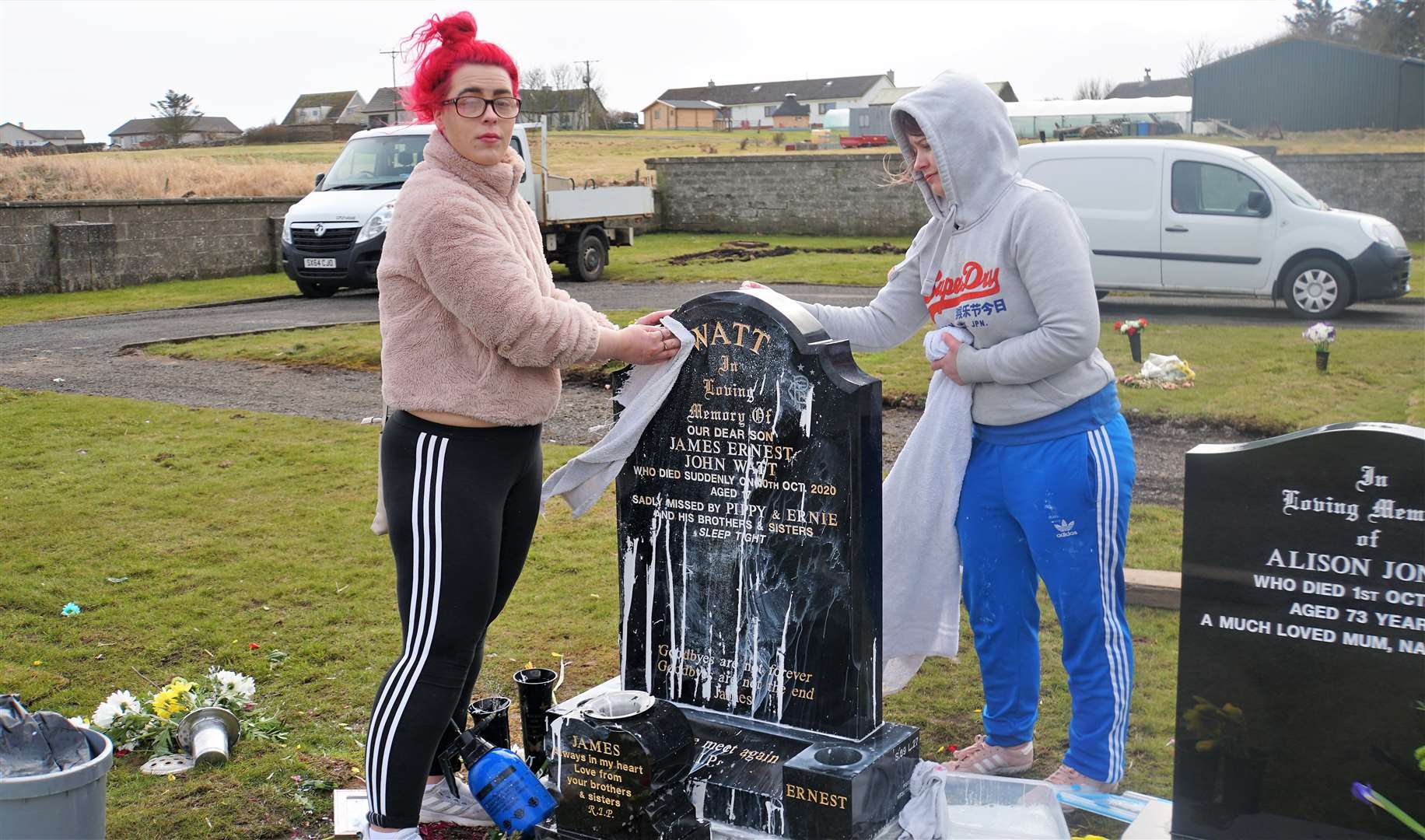 Frances Watt, left, and her sister Priscilla clean their brother's gravestone at Wick cemetery after it was splashed with white paint.