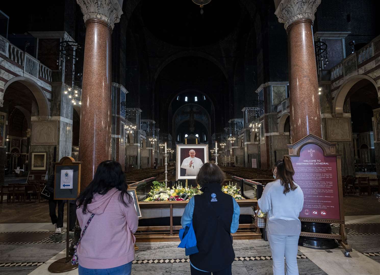 People looking at a photo of Pope Francis at Westminster Cathedral in central London, on the day of the Pope’s funeral (Jeff Moore/PA)
