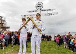Andrew Sinclair (left) and Louis Mackinnon with the Olympic flame at John O’Groats. Photo: Robert MacDonald / Northern Studios.