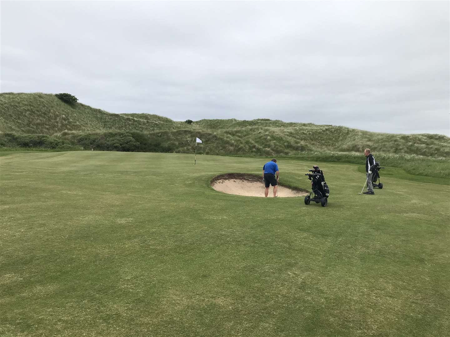 Mike Halliday playing from the bunker at the sixth at Reay as Murdo Macdonald looks on.