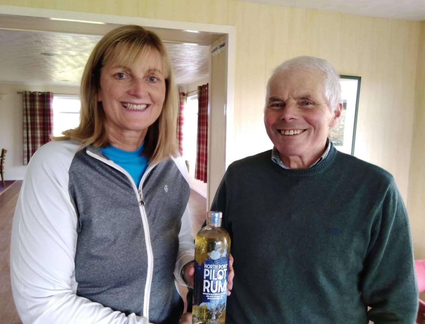 Carol Paterson, winner of the North Point Senior Stableford competition, receiving a bottle of rum from senior section convener Sandy Chisholm. She also bagged the nearest-the-pin prize.