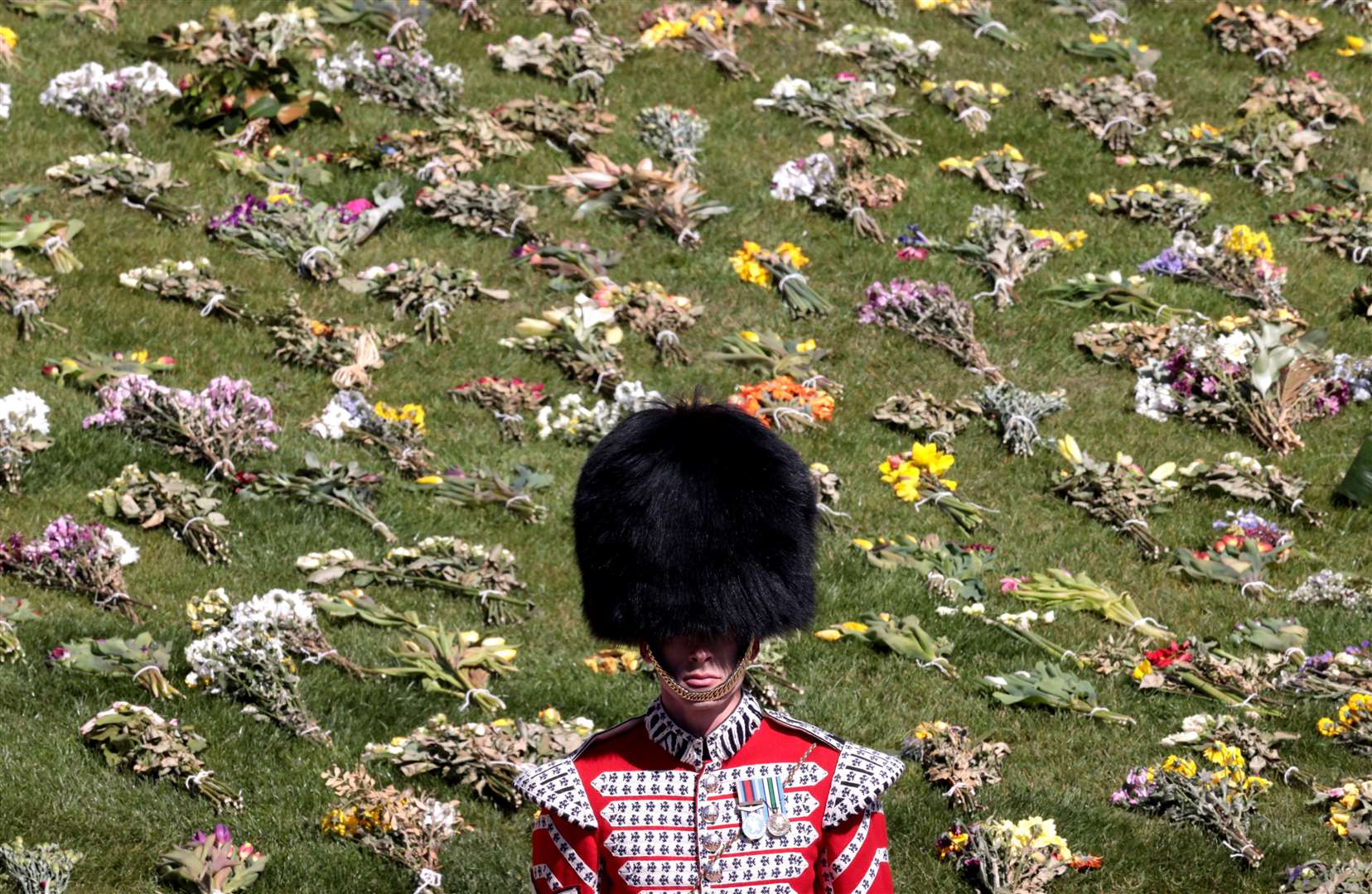 A guard stands in front of flowers laid out on the grass outside St George’s Chapel, Windsor Castle (Hannah McKay/PA)
