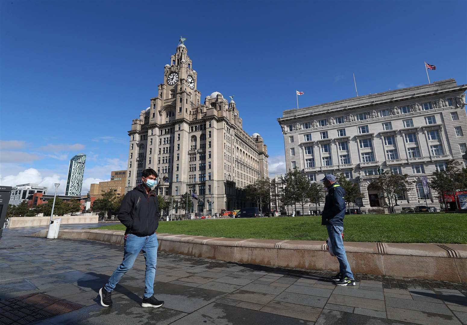 A man in a face mask walks past the Liver Building in Liverpool (Peter Byrne/PA)