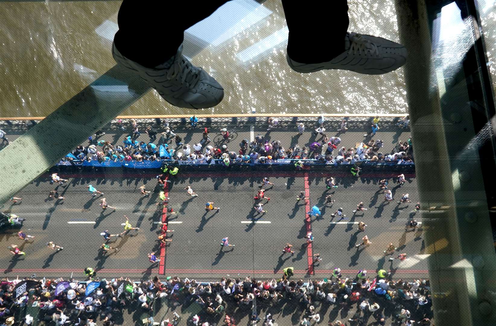 Visitors to Tower Bridge walk across the walkway as the race progresses below (Jonathan Brady/PA)