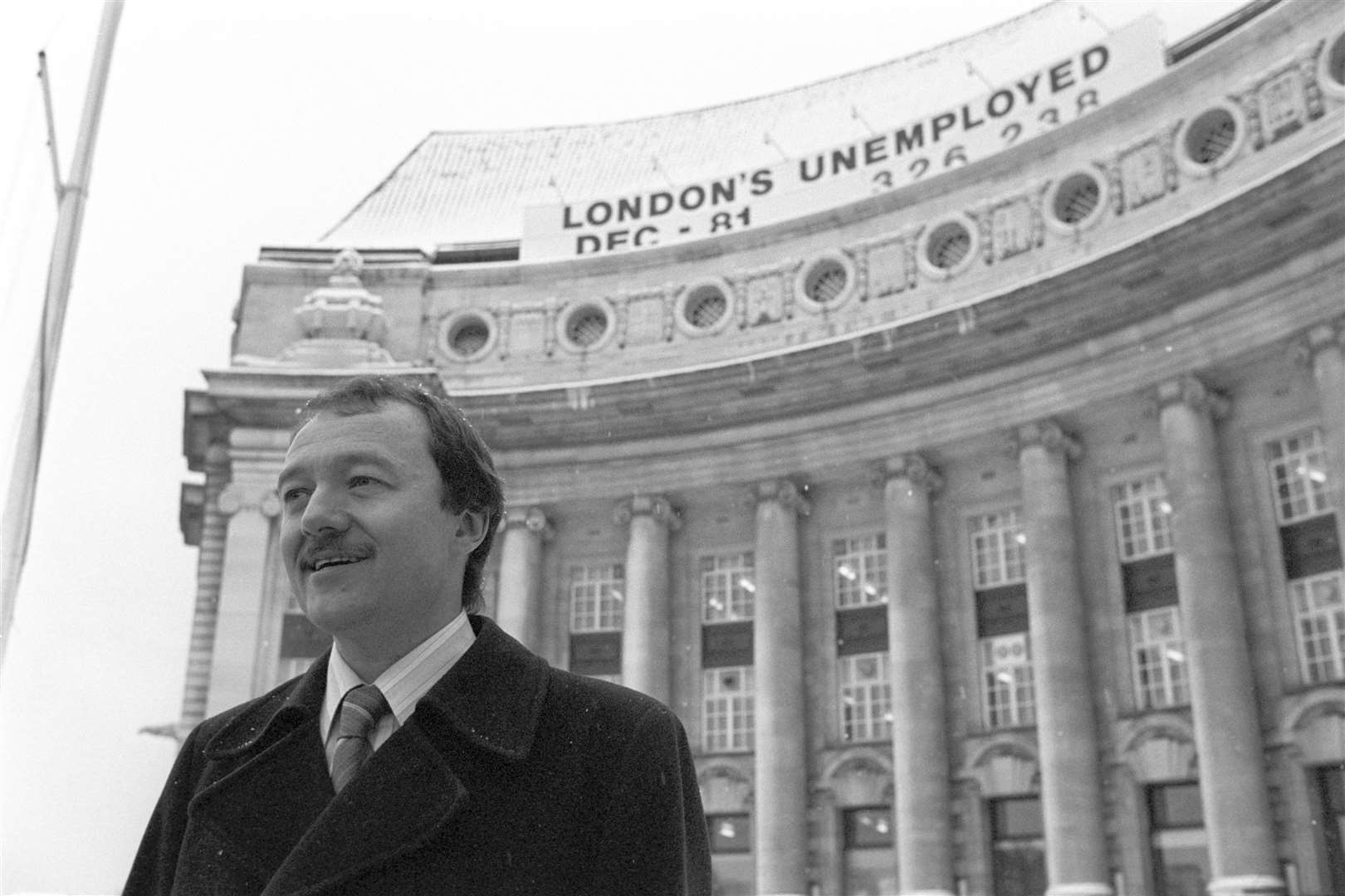 GLC leader Ken Livingstone beneath the giant sign erected on the roof of County Hall showing the number of people out of work in Greater London (PA)