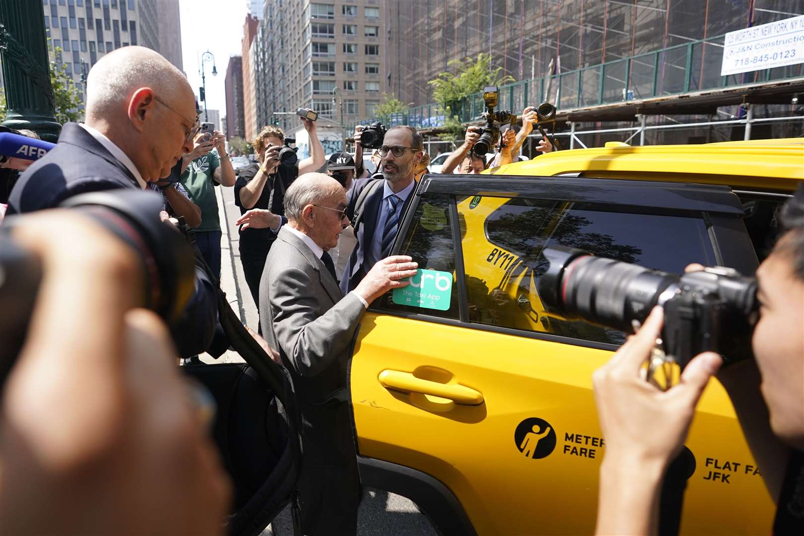Tavistock founder Joe Lewis, centre, is surrounded by photographers as he leaves Manhattan federal court (Mary Altaffer/AP)