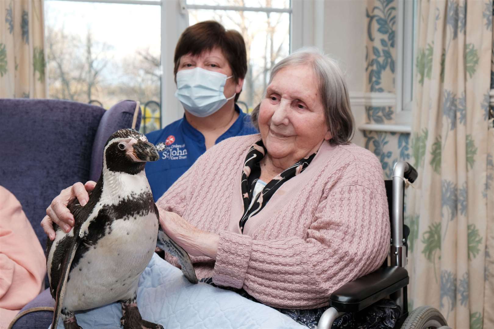 One of the penguins perched on a resident’s lap (Des Dubber/Orders of Saint John Care Trust/PA)