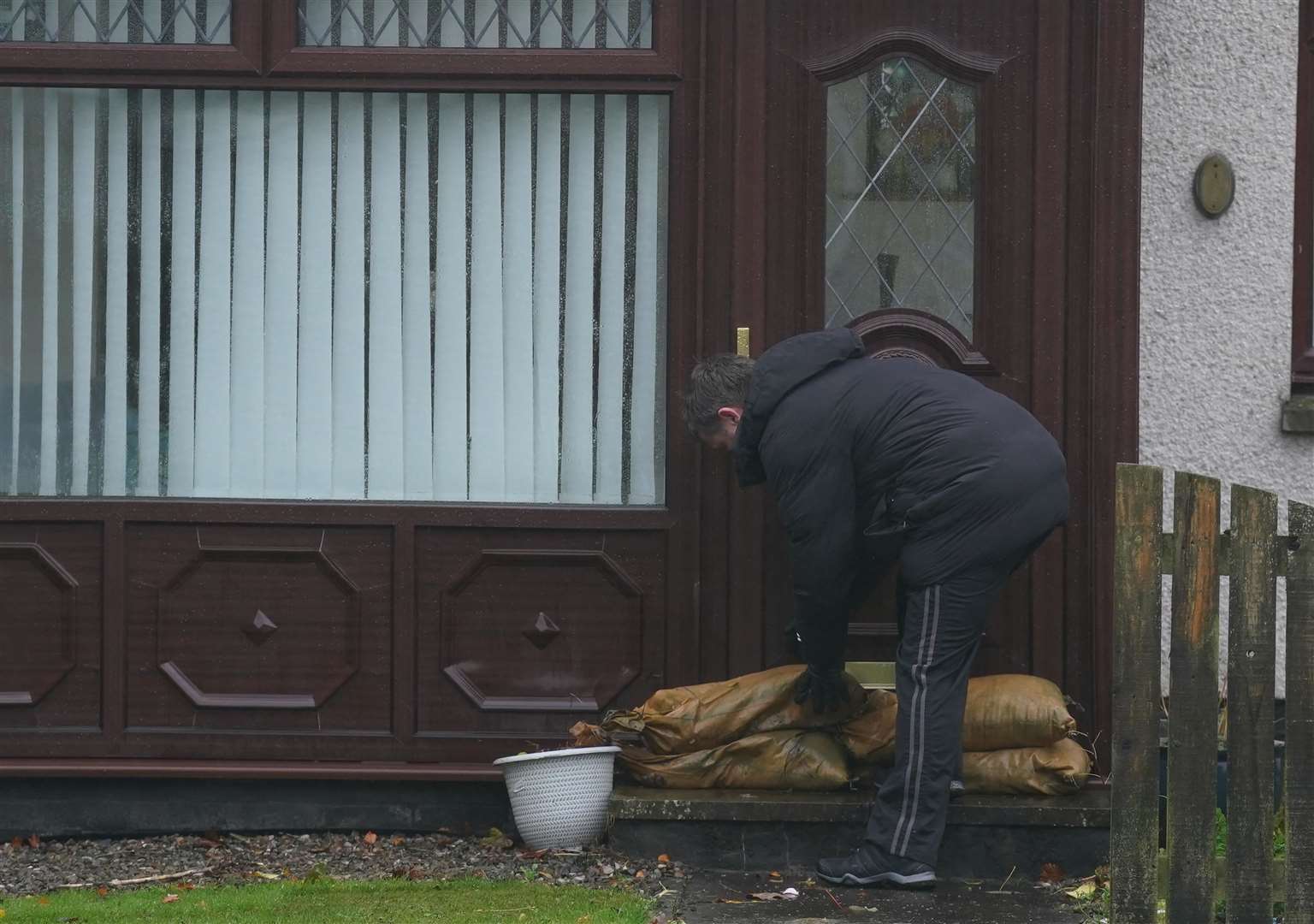 A resident puts sand bags outside his door as he leaves his house on River Street in Brechin, Scotland (Andrew Milligan/PA)