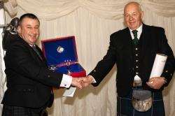Sandy Taylor (right) accepts the award from distillery manager Malcolm Waring.