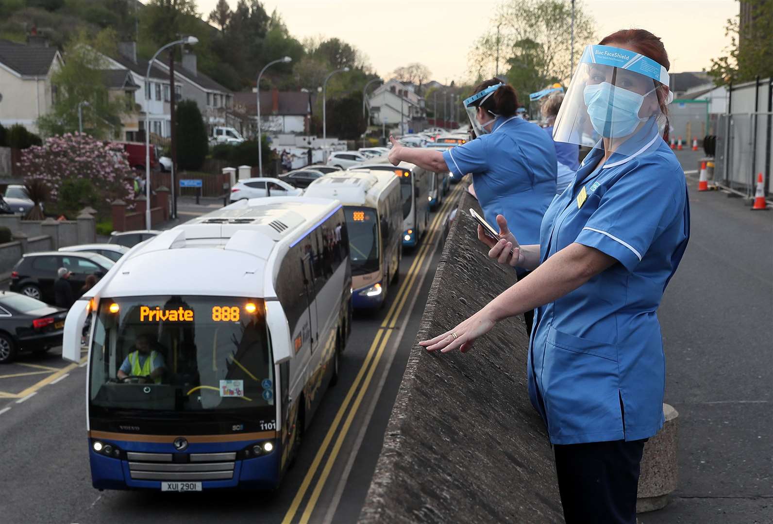 Healthcare workers watch as a convoy of buses beeping their horns passes Daisy Hill Hospital in Newry during Clap for Carers in April (Brian Lawless/PA)