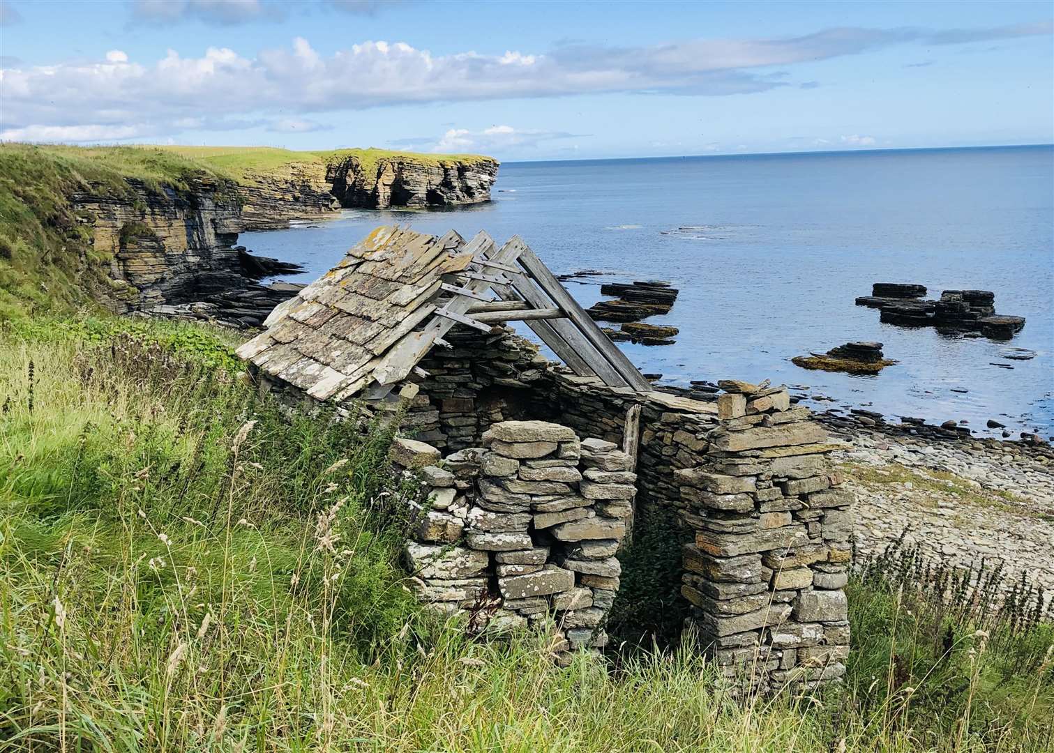 The old fisherman’s bothy at the old harbour at Nybster with the rugged cliffs of Caithness in the background, pictured by Lyall Rennie.