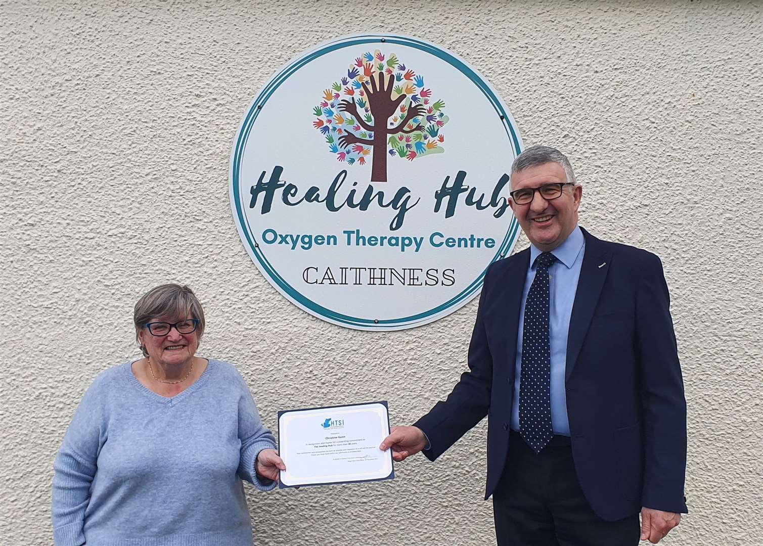Chrissie Gunn receiving her Highland Third Sector Interface volunteering award from Willie Watt, Vice-Lieutenant of Caithness, outside the Healing Hub in Wick.