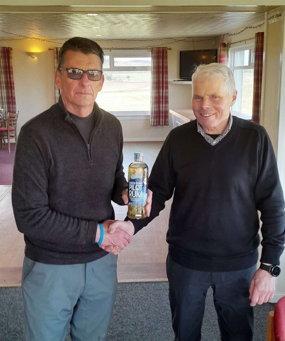 Malcolm Thomson receiving a bottle of North Point Gin from senior section convener Sandy Chisholm after winning the nearest-the-pin prize in the latest round of the Senior Stableford competition.