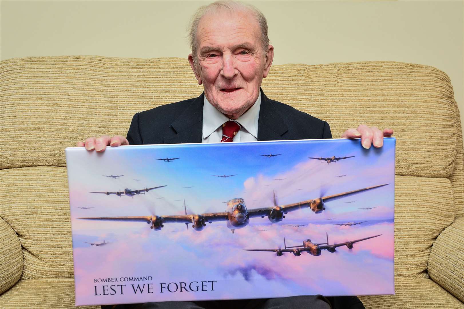 George ‘Johnny’ Johnson photographed in 2017 at his home in Bristol holding a picture of Lancaster bombers (Ben Birchall/PA)