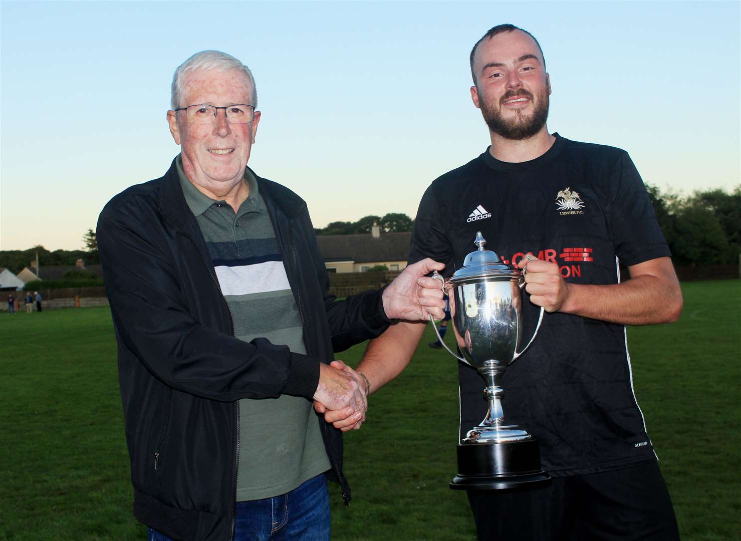 Caithness AFA president Murray Coghill hands over the second division trophy to Lybster captain Gary Swanson. Picture: Alan Hendry