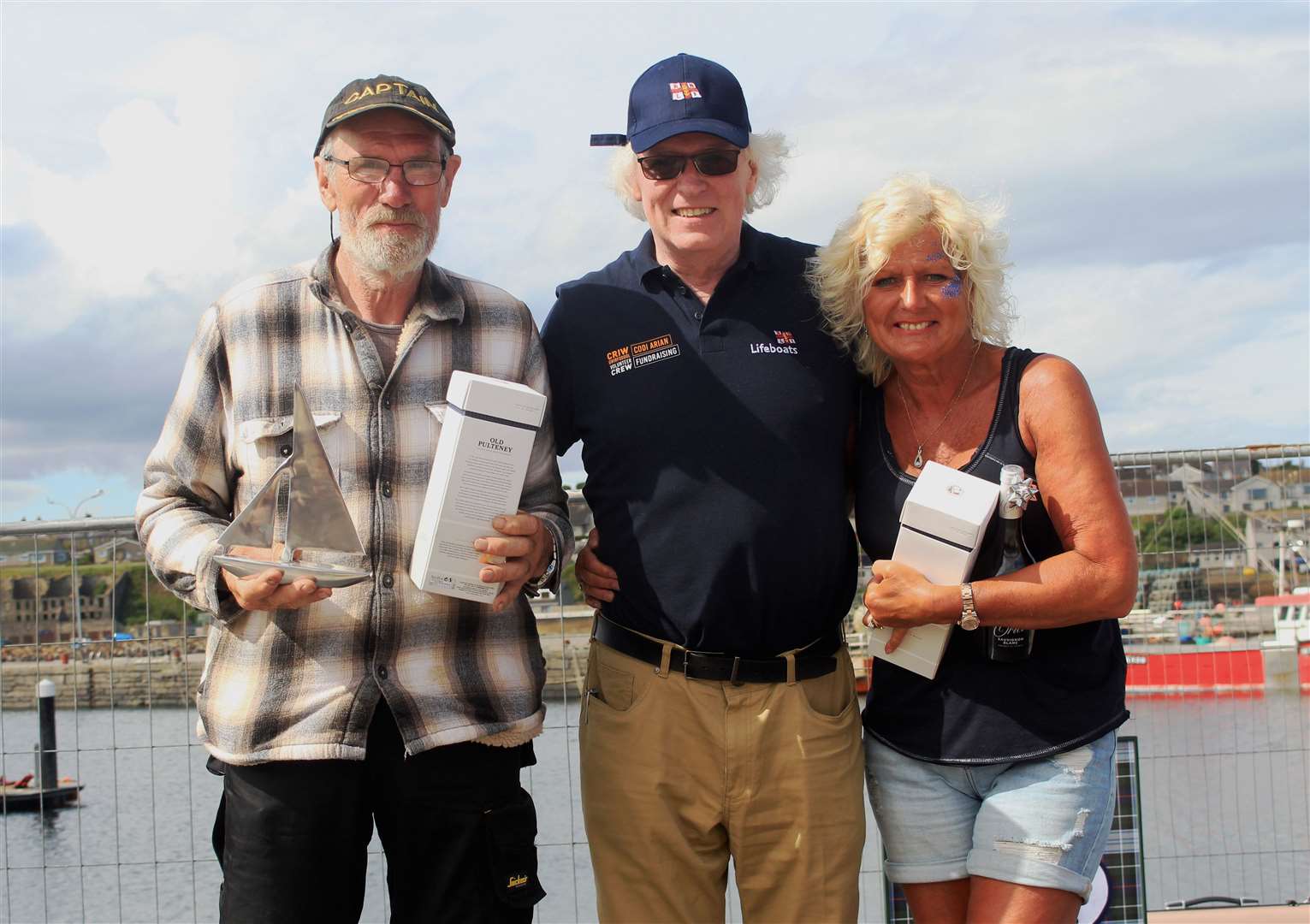 Murray Lamont (centre), chairman of the Wick lifeboat management committee, handing over the prizes for best-dressed local and visiting boats to George Durrand and Mairi Innes. Picture: Alan Hendry