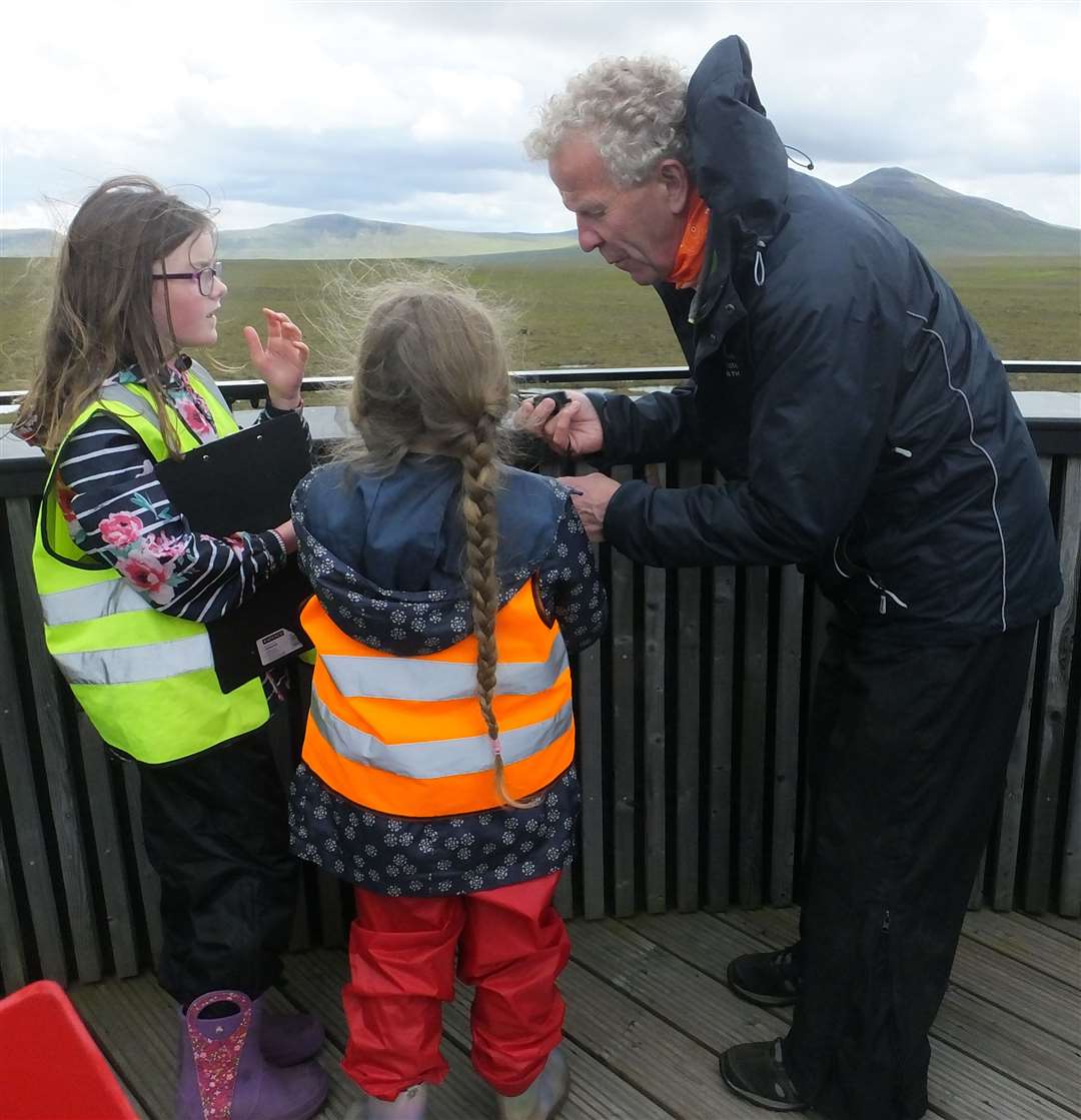 Volunteer Brian Johnston shows the Dunbeath schoolchildren how to use binoculars.