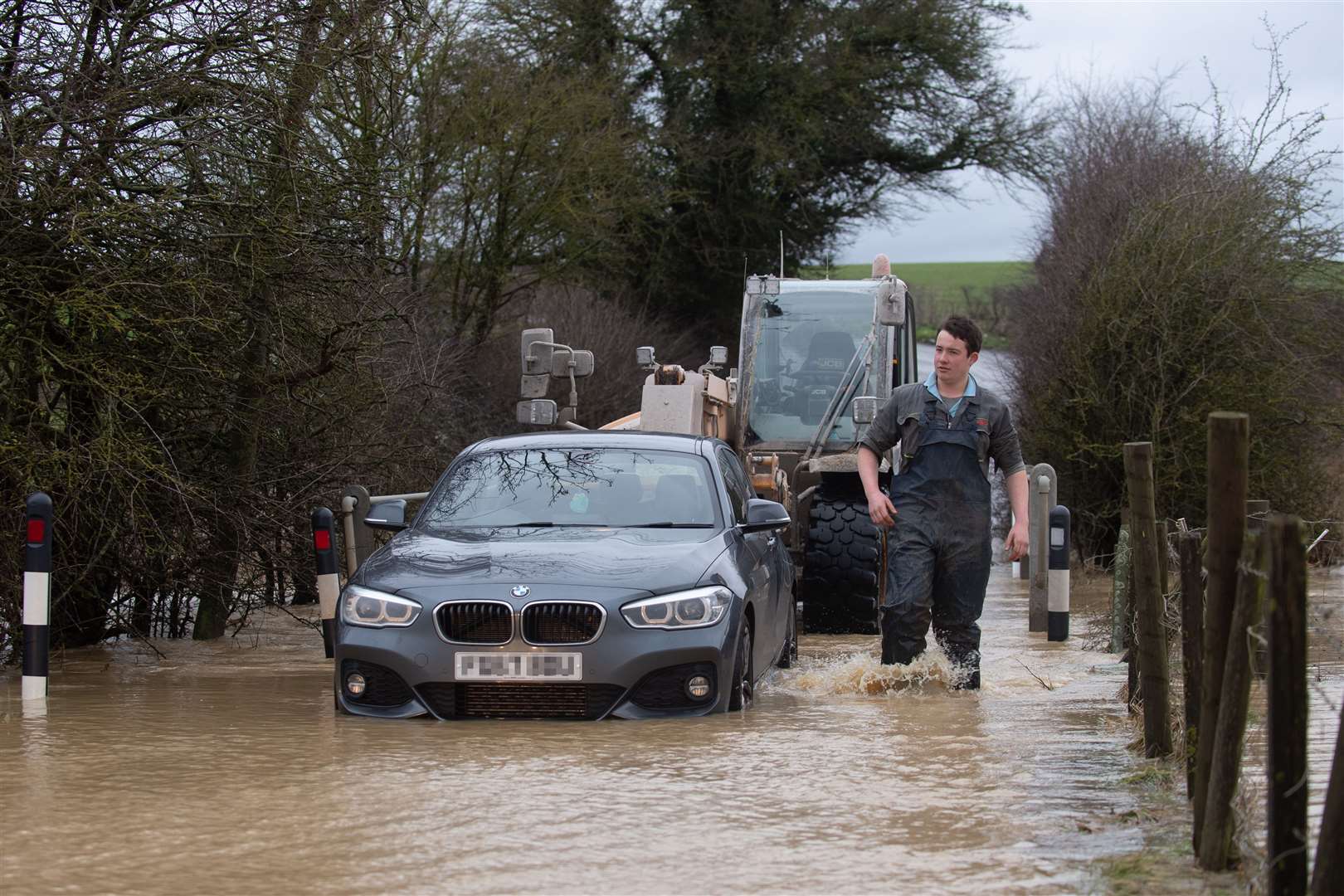 A local farmer helps rescue a stranded motorist from a flood on Hamilton Road in Leicester (Joe Giddens/PA)