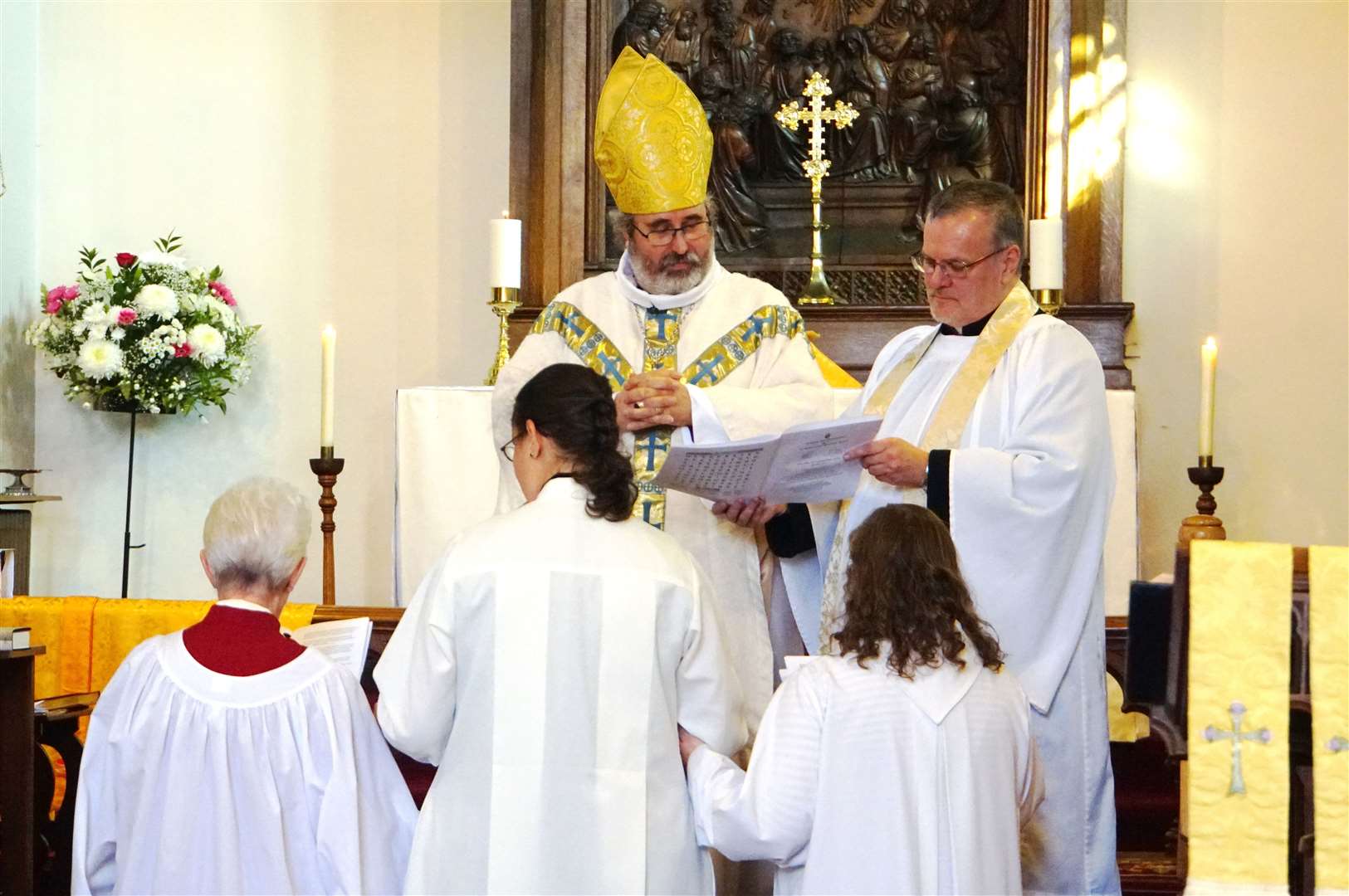 Bishop Mark Strange in the act of ordaining Ellie Charman.