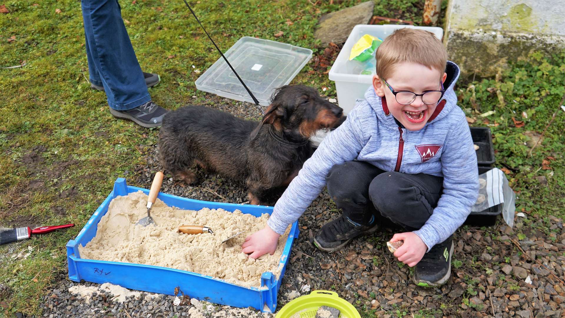 Young Jordan and Lilly the dachshund dig for archaeological treasures in a sand pit. Picture: DGS
