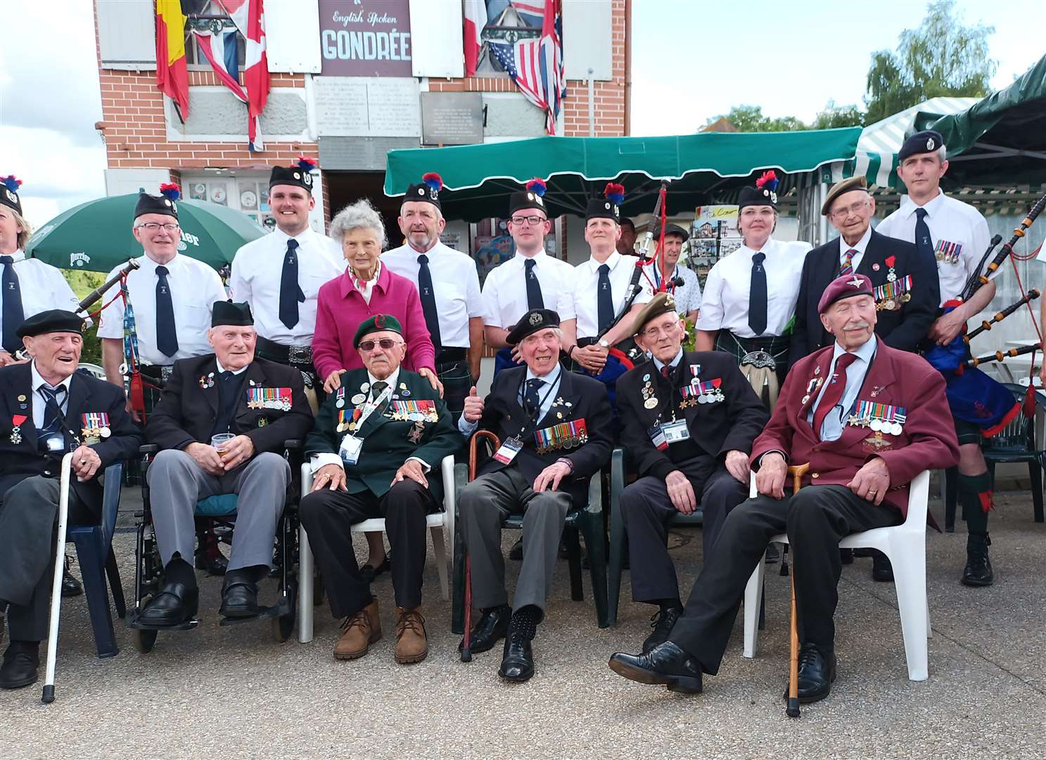 Robbie Larnach (seated, second from right), outside the Café Gondrée at Pegasus Bridge with other veterans and members of Jedburgh Pipe Band, June 2022.