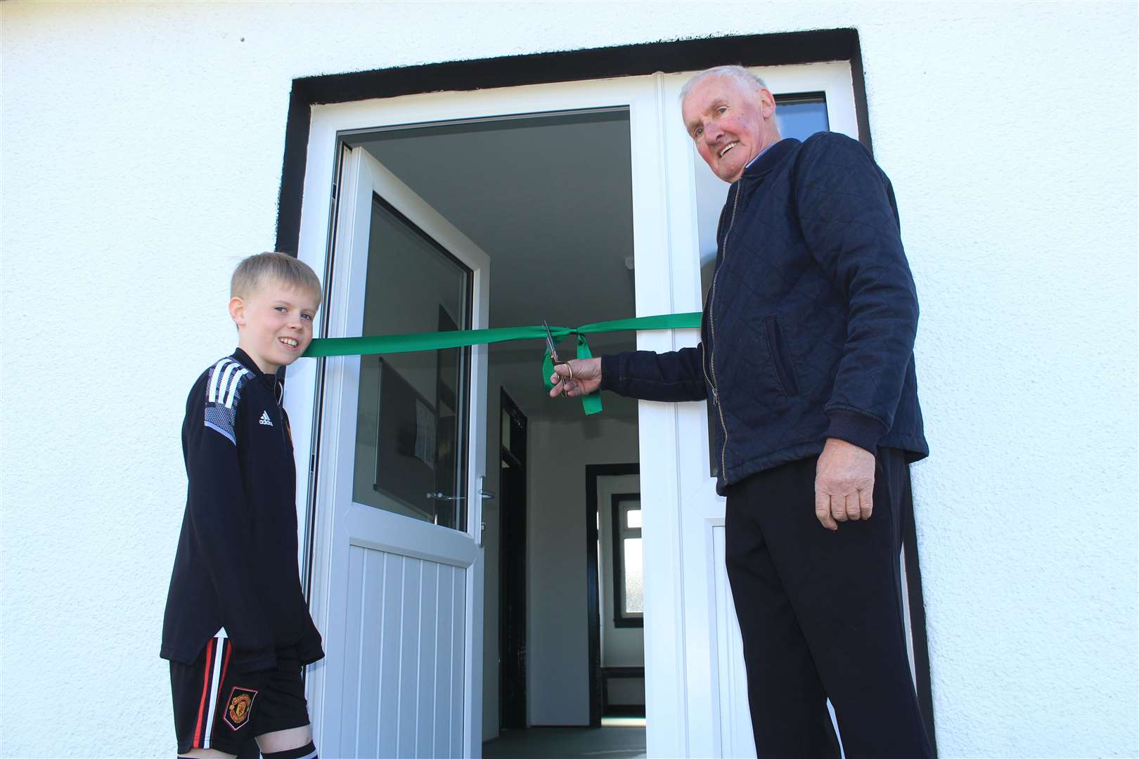 Club president Jimmy Gunn cutting the ribbon at the refurbished Castletown pavilion, along with his nine-year-old grandson Kian Sutherland. Picture: Alan Hendry