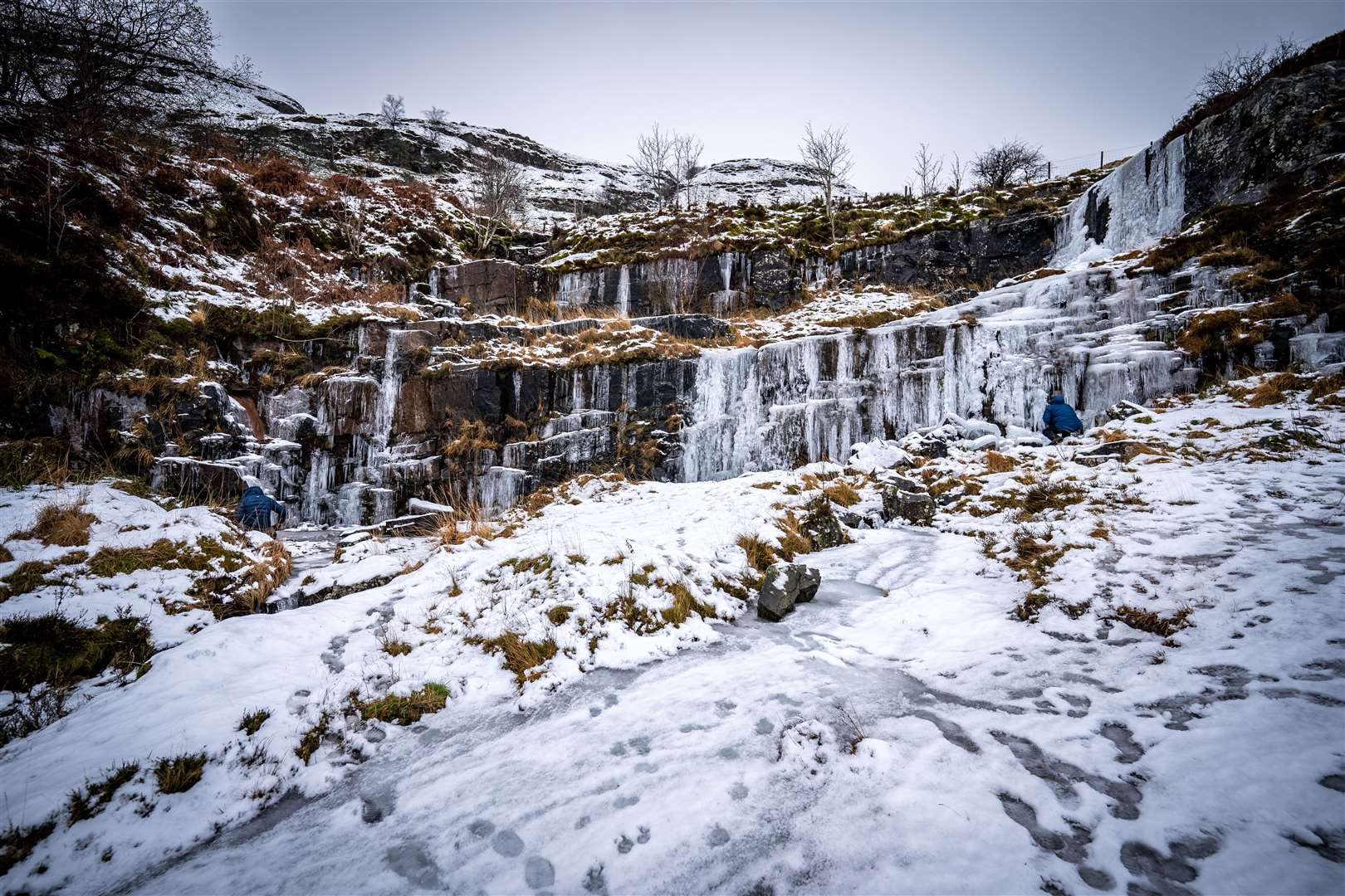 People look at icicle formations at a frozen waterfall in the Brecon Beacons National Park (Ben Birchall/PA)