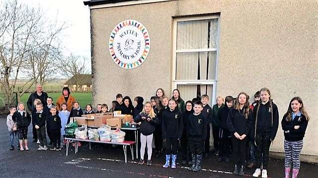 Watten P1-7 pupils with Pat and Grant Ramsay, at left, and the foodbank donations.