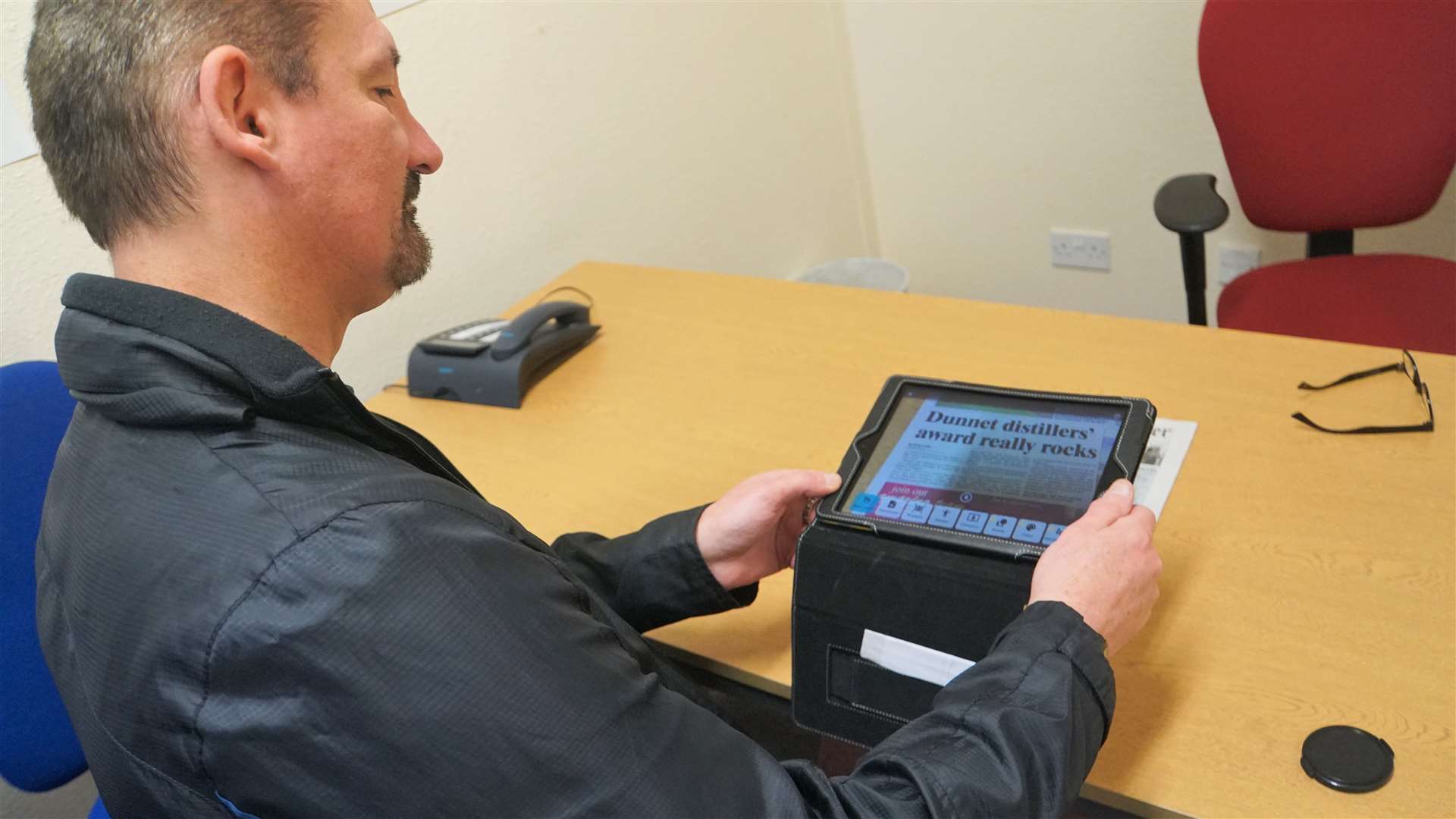 Jamie shows how a special app on his tablet can read aloud the text in a Caithness Courier article to help people with sight issues. Picture: DGS