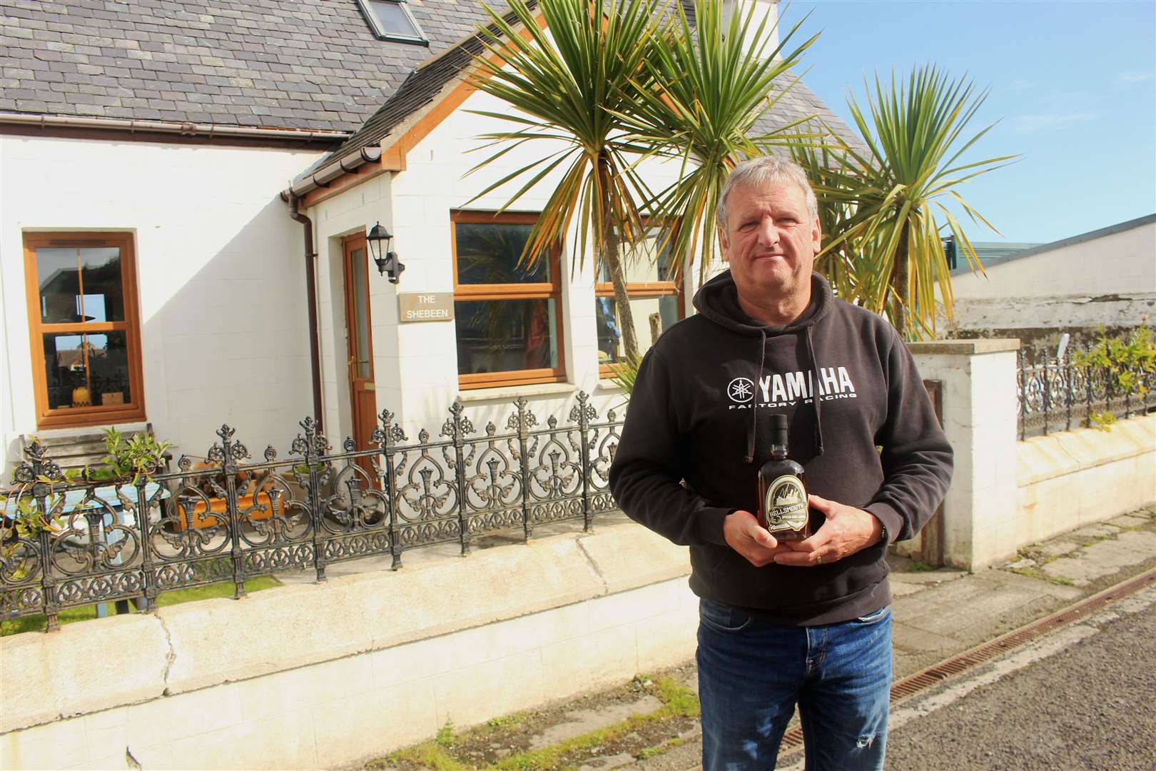 David Carter outside his house, The Shebeen, holding a bottle of Hellsmouth spiced rum.