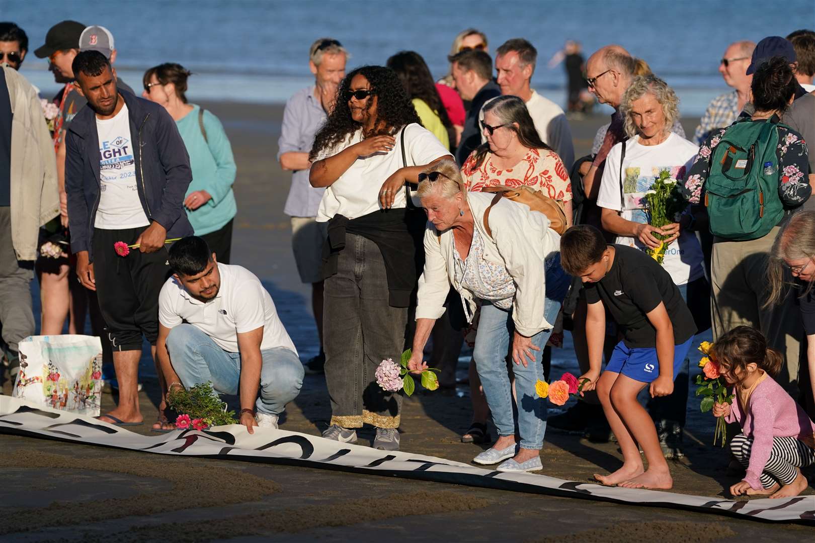 People lay flowers at a vigil at Sunny Sands Beach in Folkestone (Gareth Fuller/PA)