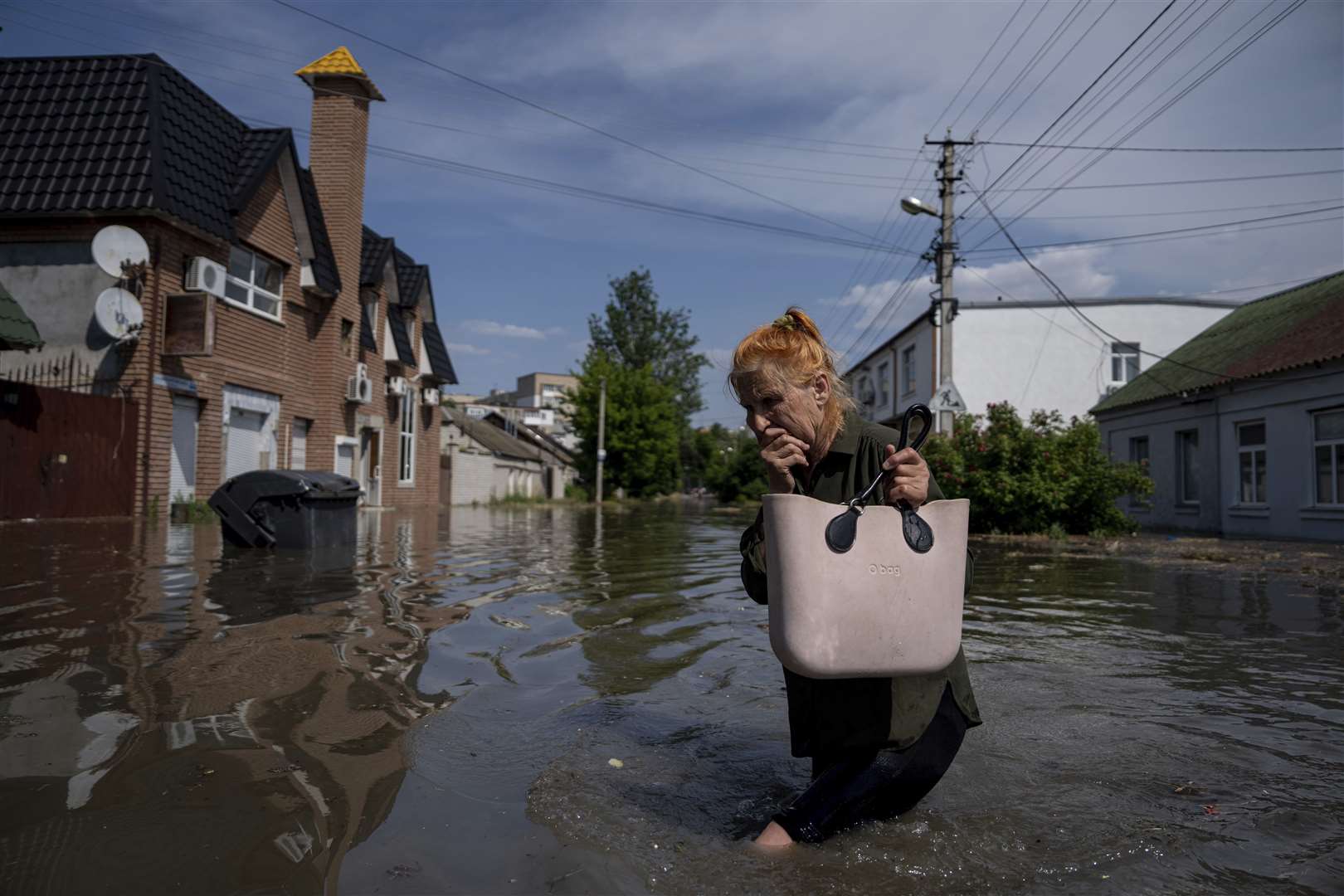 A resident makes her way through a flooded road after the walls of the Kakhovka dam collapsed overnight (Evgeniy Maloletka/AP/PA)