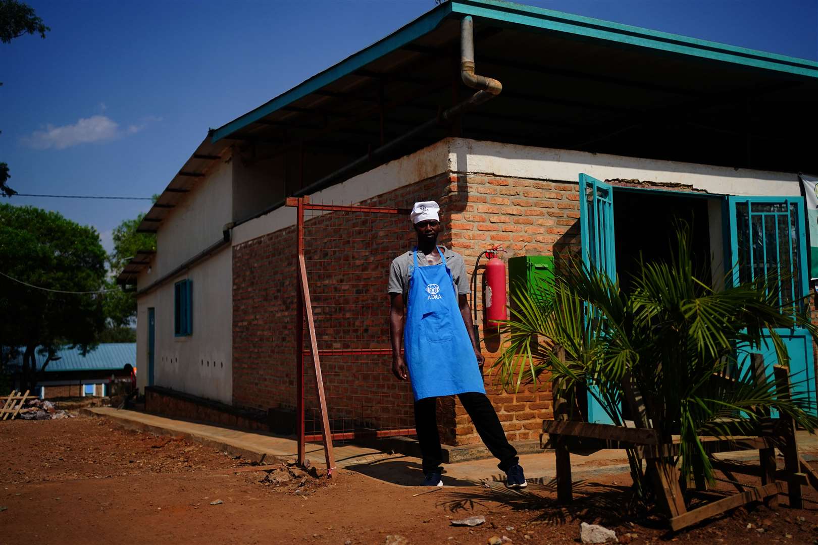 A kitchen worker stands outside the canteen at Gashora Refugee Camp Transit Centre (Victoria Jones/PA)